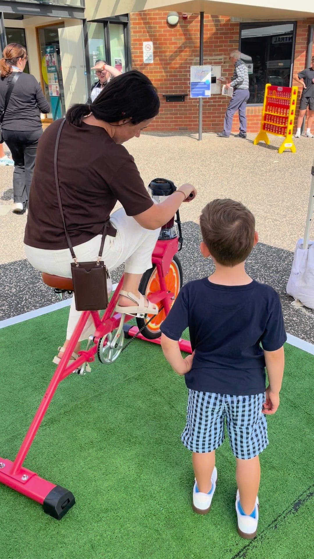 A parent helps a child onto the smoothie bike